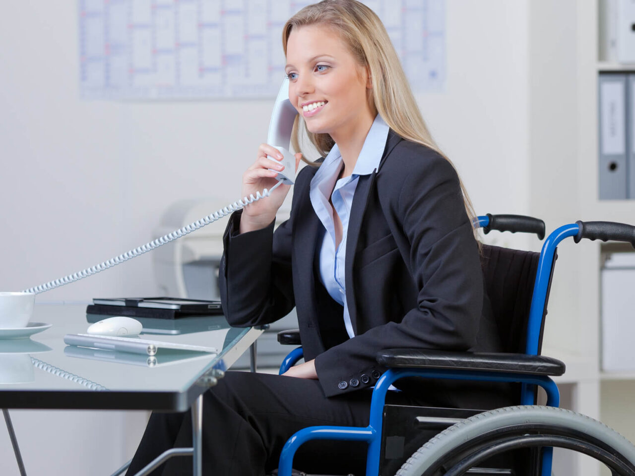 Woman in wheelchair at her desk on talking on the phone