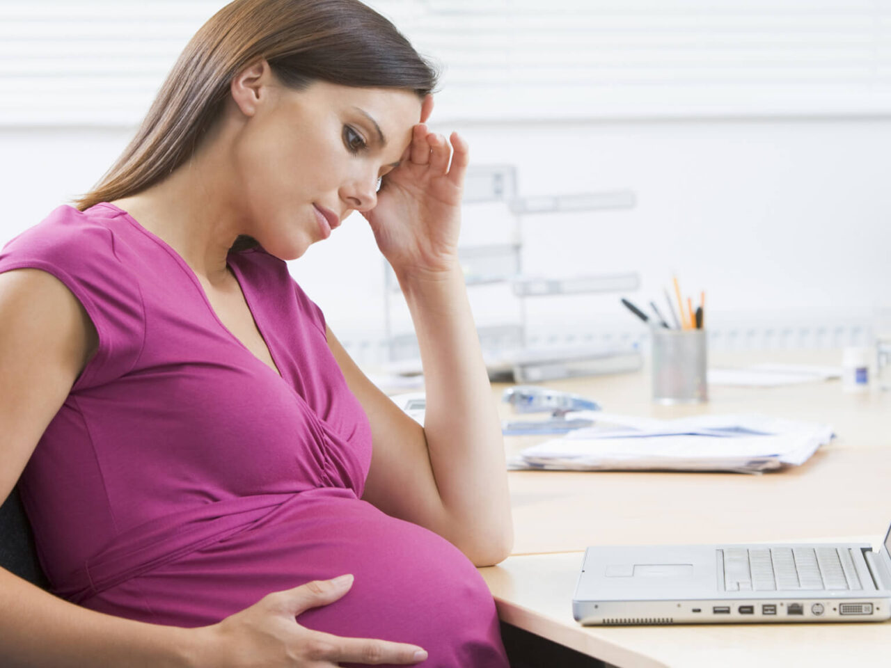 Frustrated pregnant woman sitting at a desk
