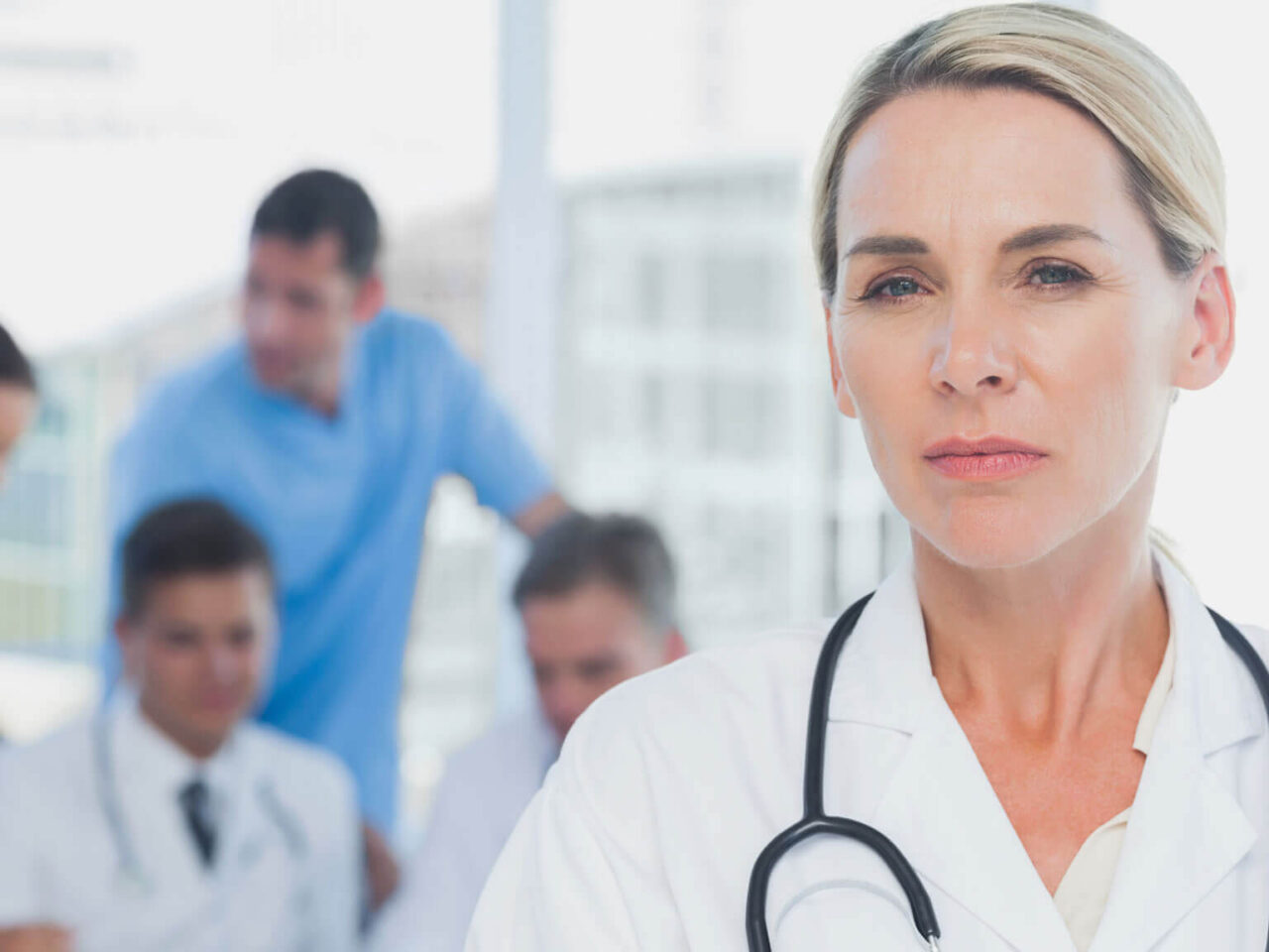 Female doctor in a white coat standing in front of a group of doctors
