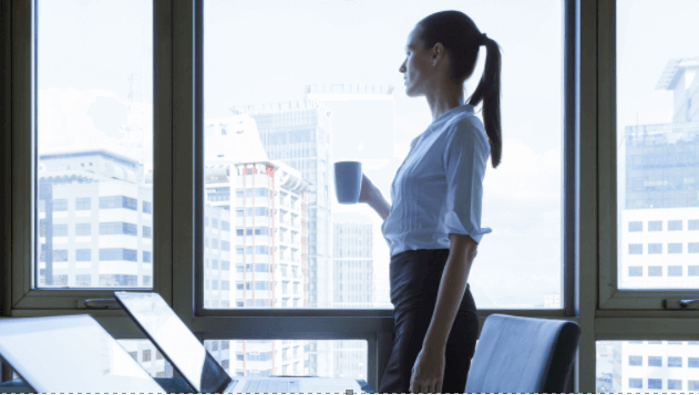 Young businesswoman standing by a window with a mug